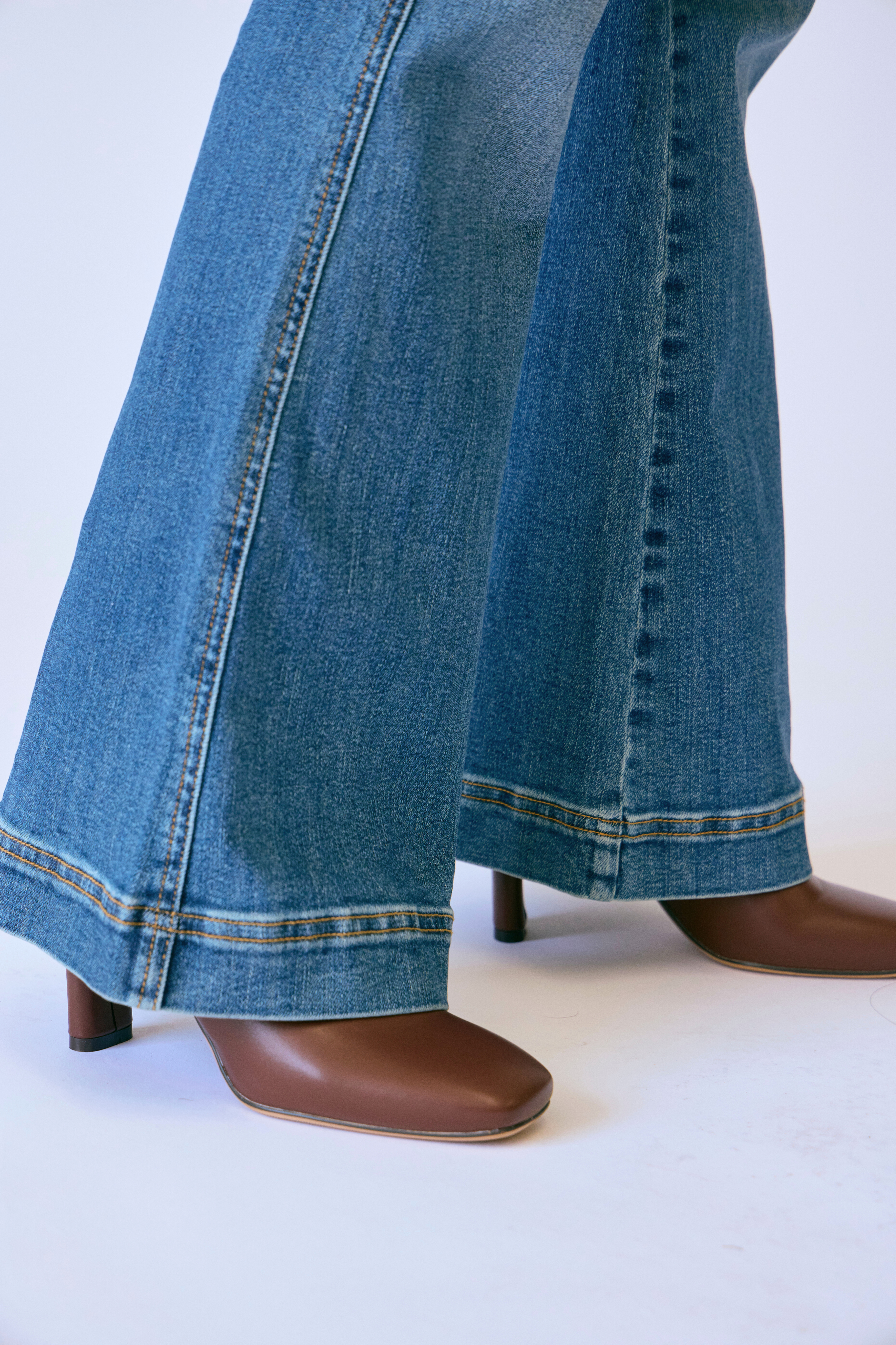 Blue jeans with a cuffed hem worn by a person on a white background