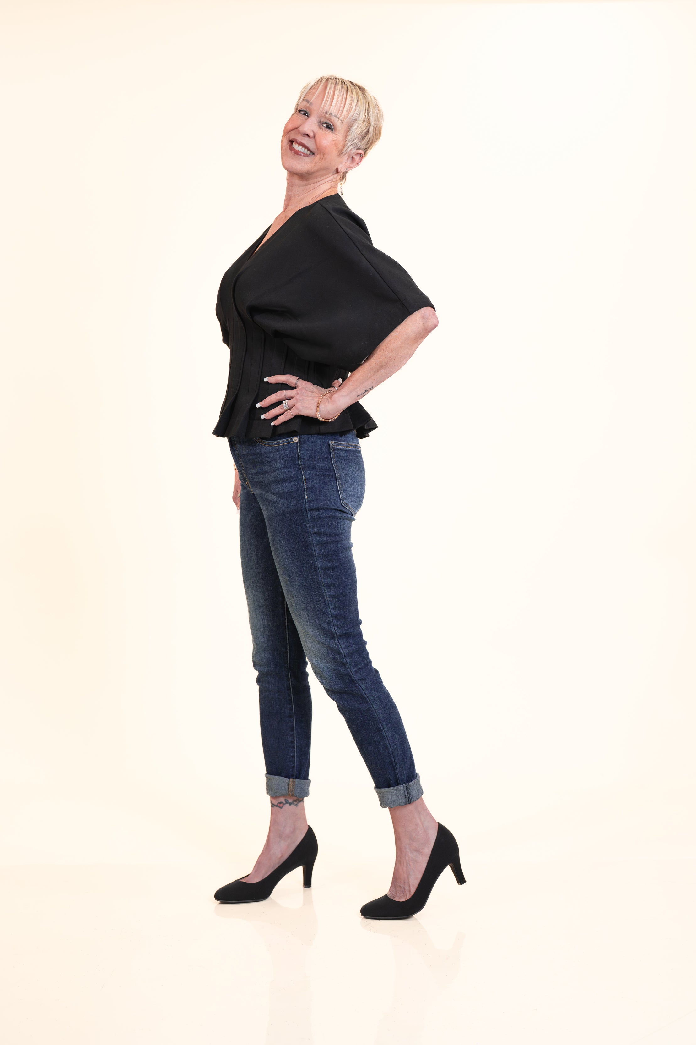 Woman wearing a black top and blue jeans on a white background