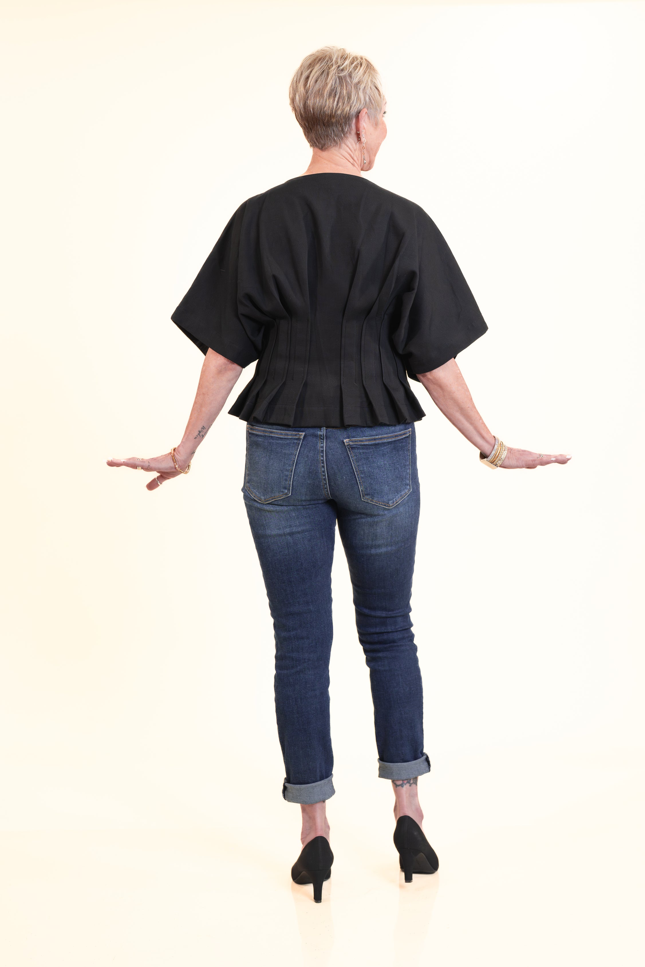 Person wearing a black top and blue jeans on a white background