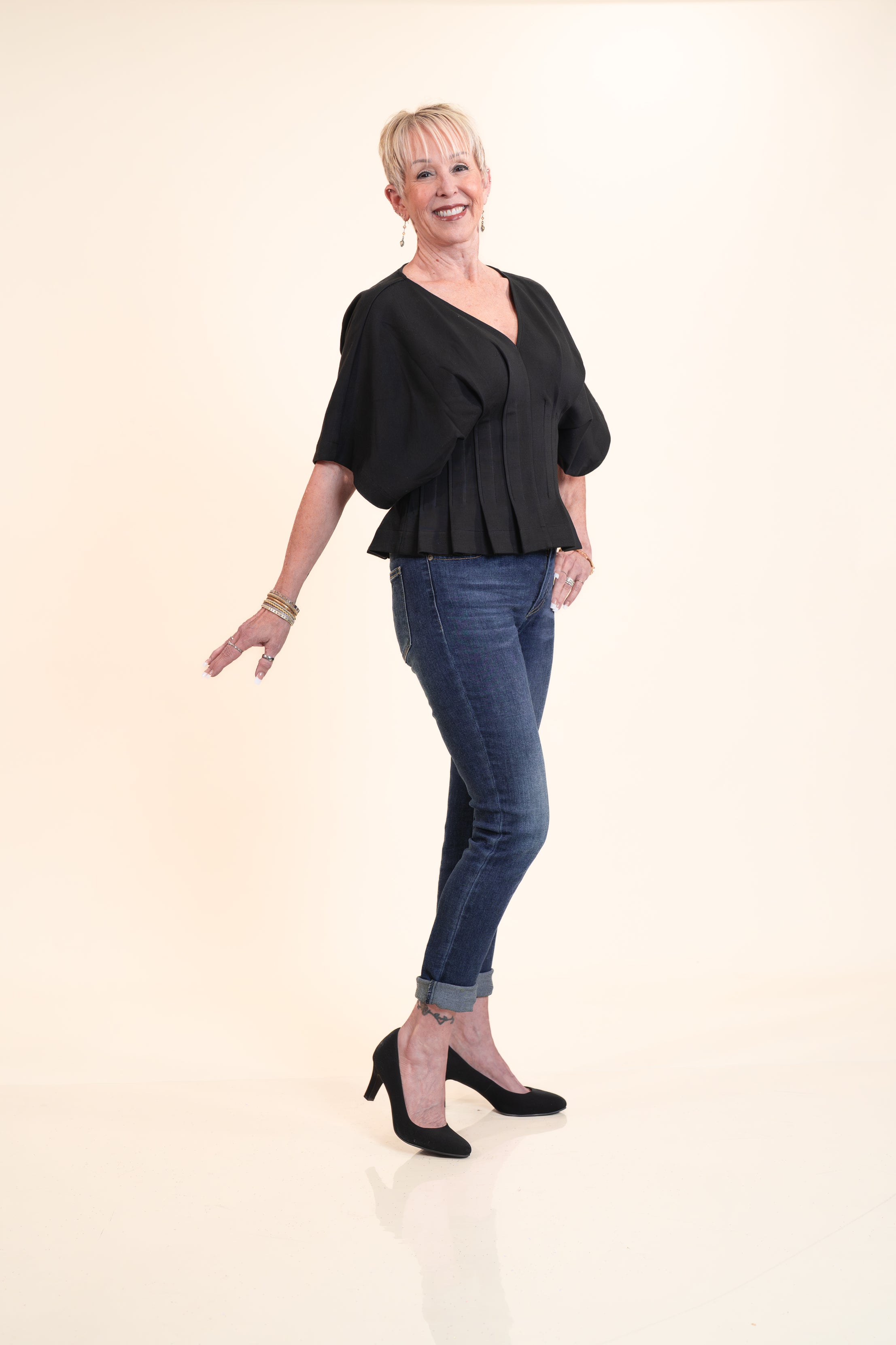 Woman wearing a black top and blue jeans on a white background