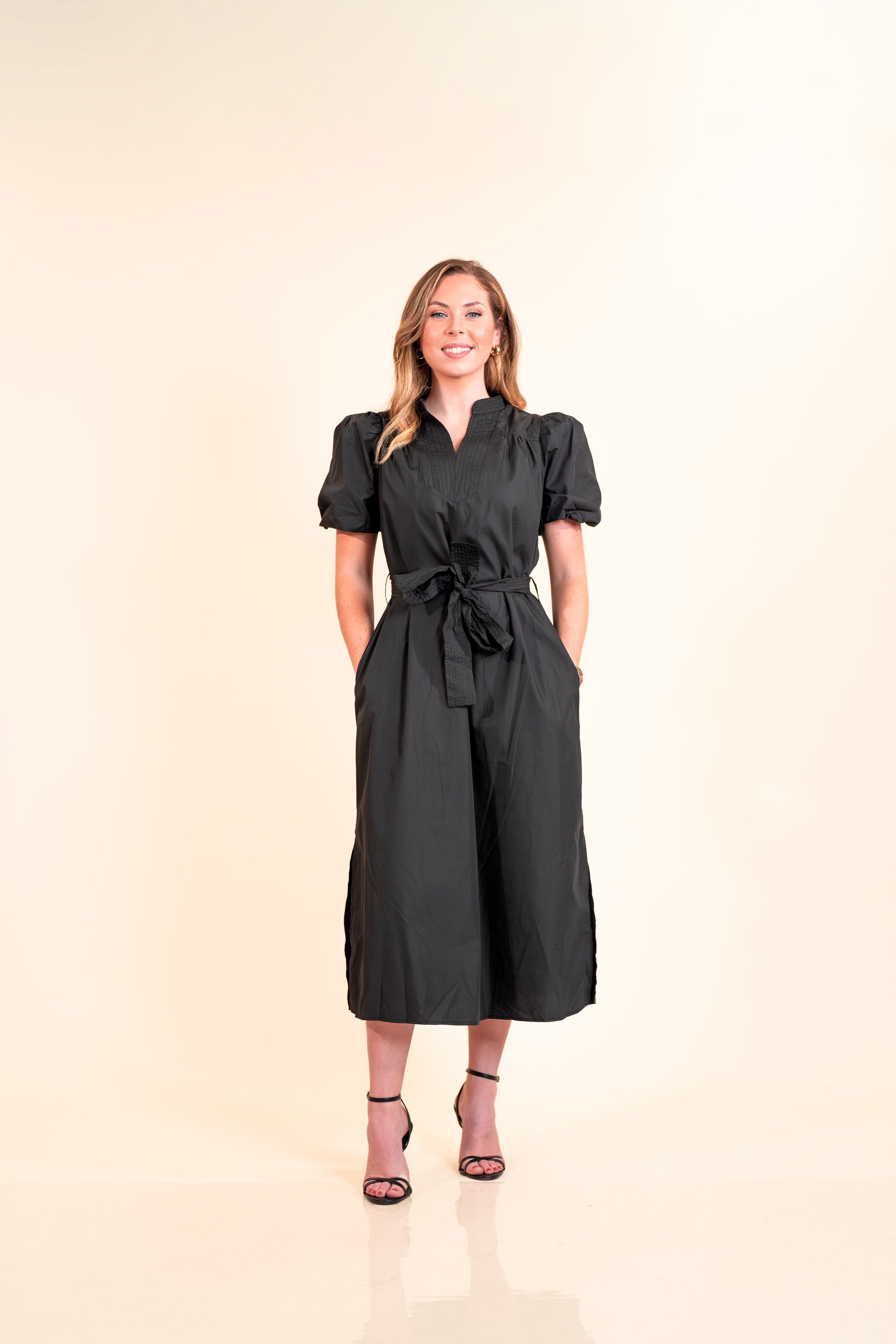 Woman wearing a black dress with puff sleeves on a beige background