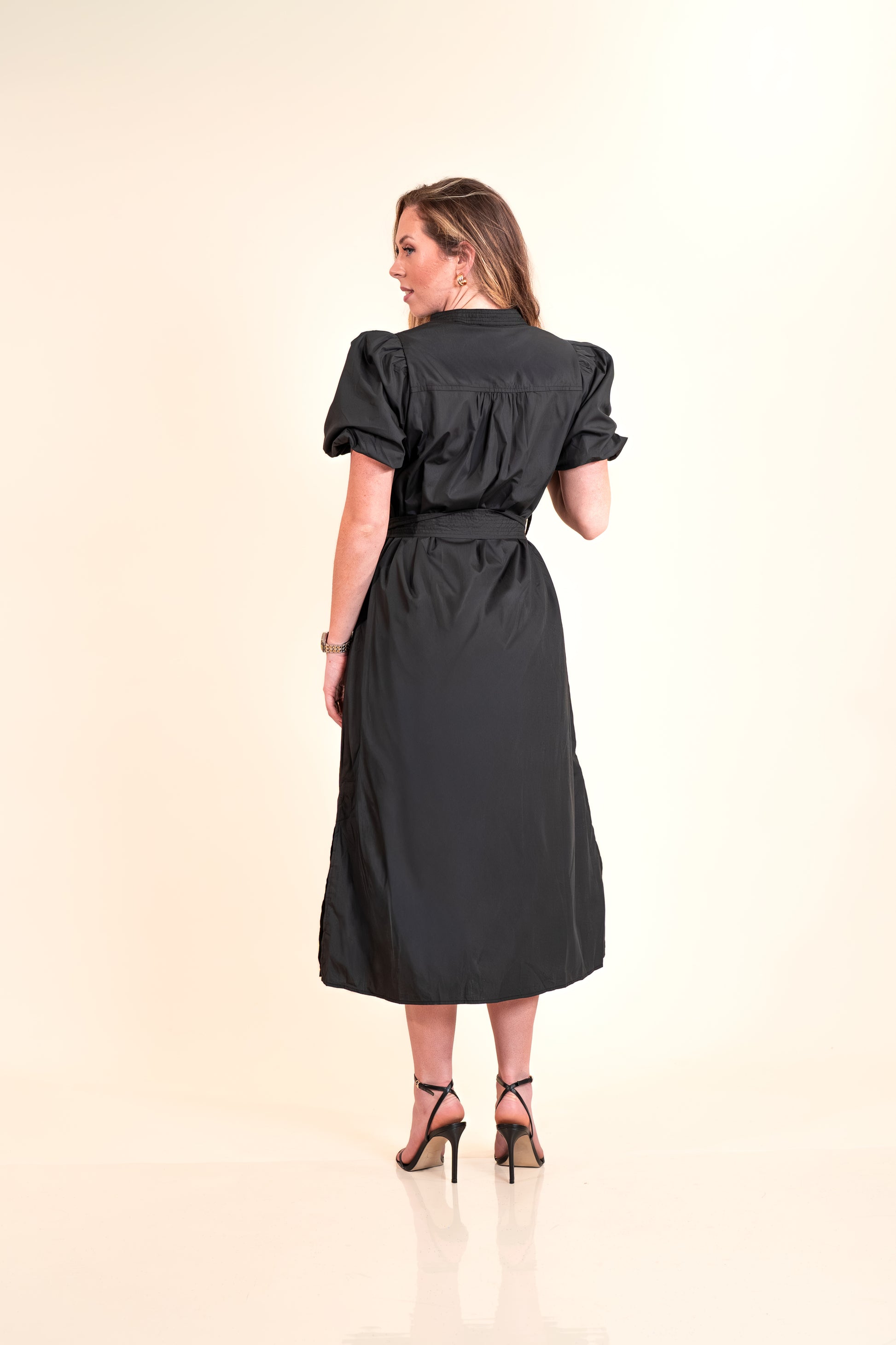 Woman wearing a black dress on a beige background