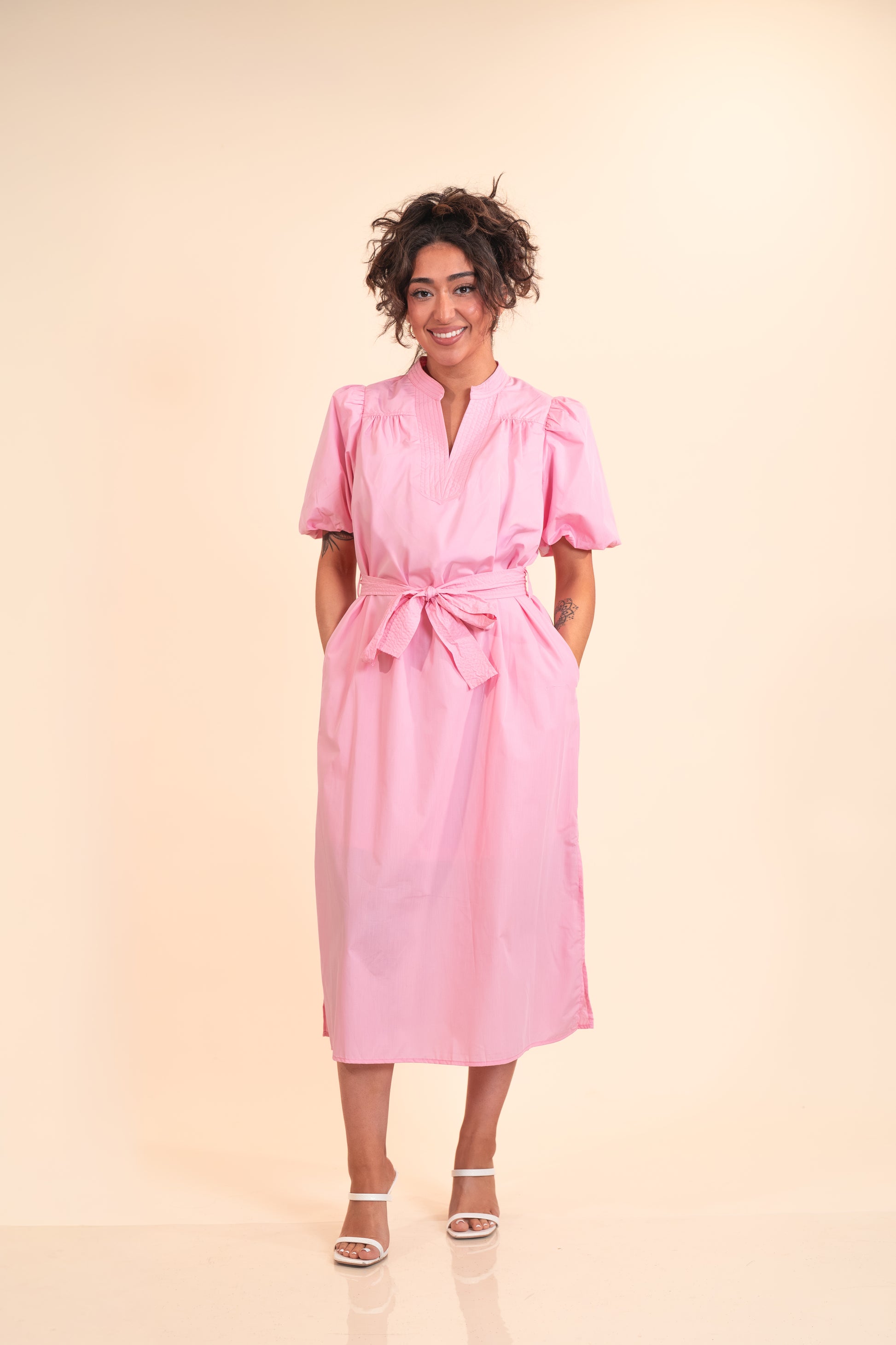 Woman wearing a pink dress against a beige background