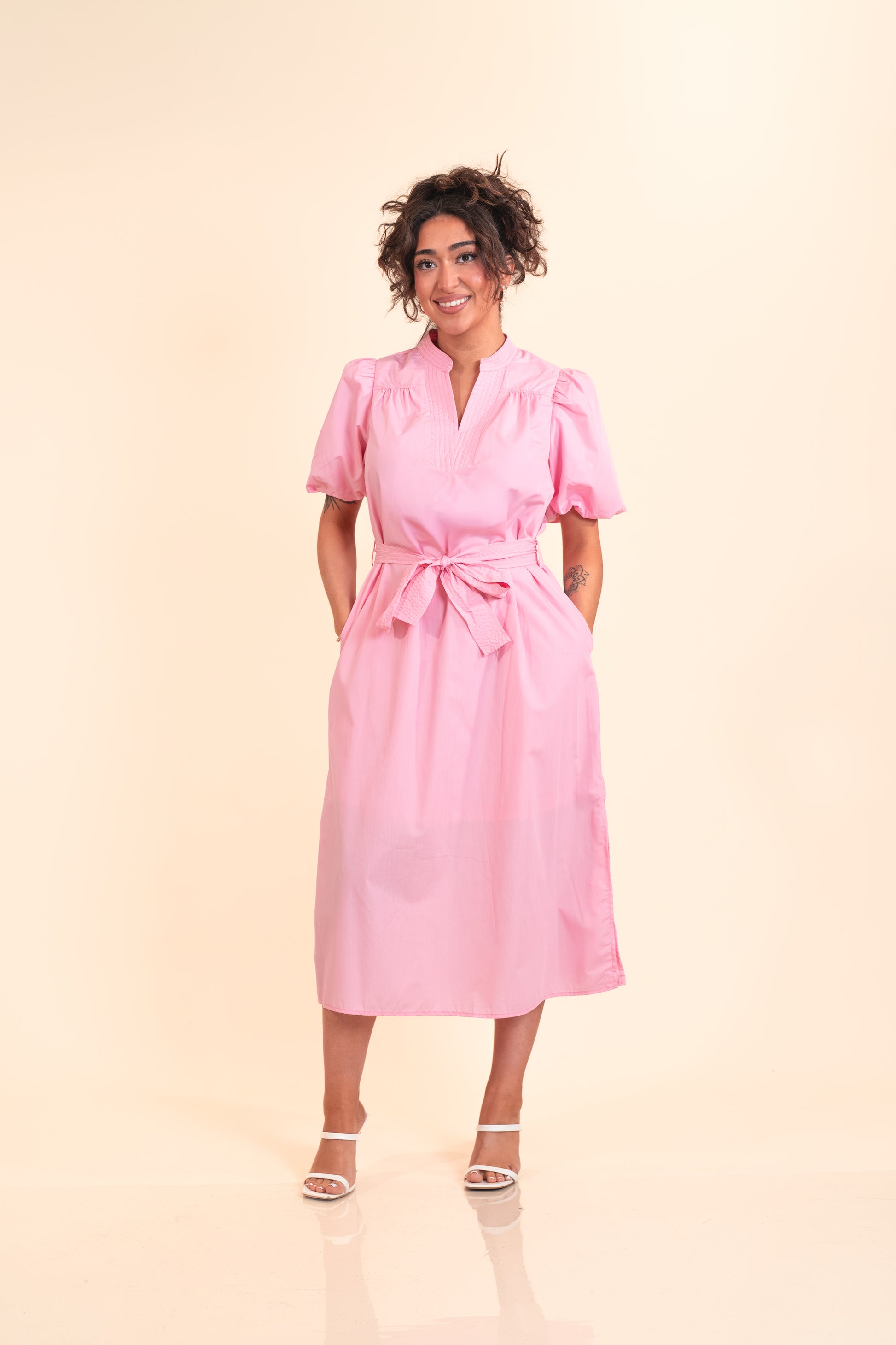 Woman wearing a pink dress against a beige background