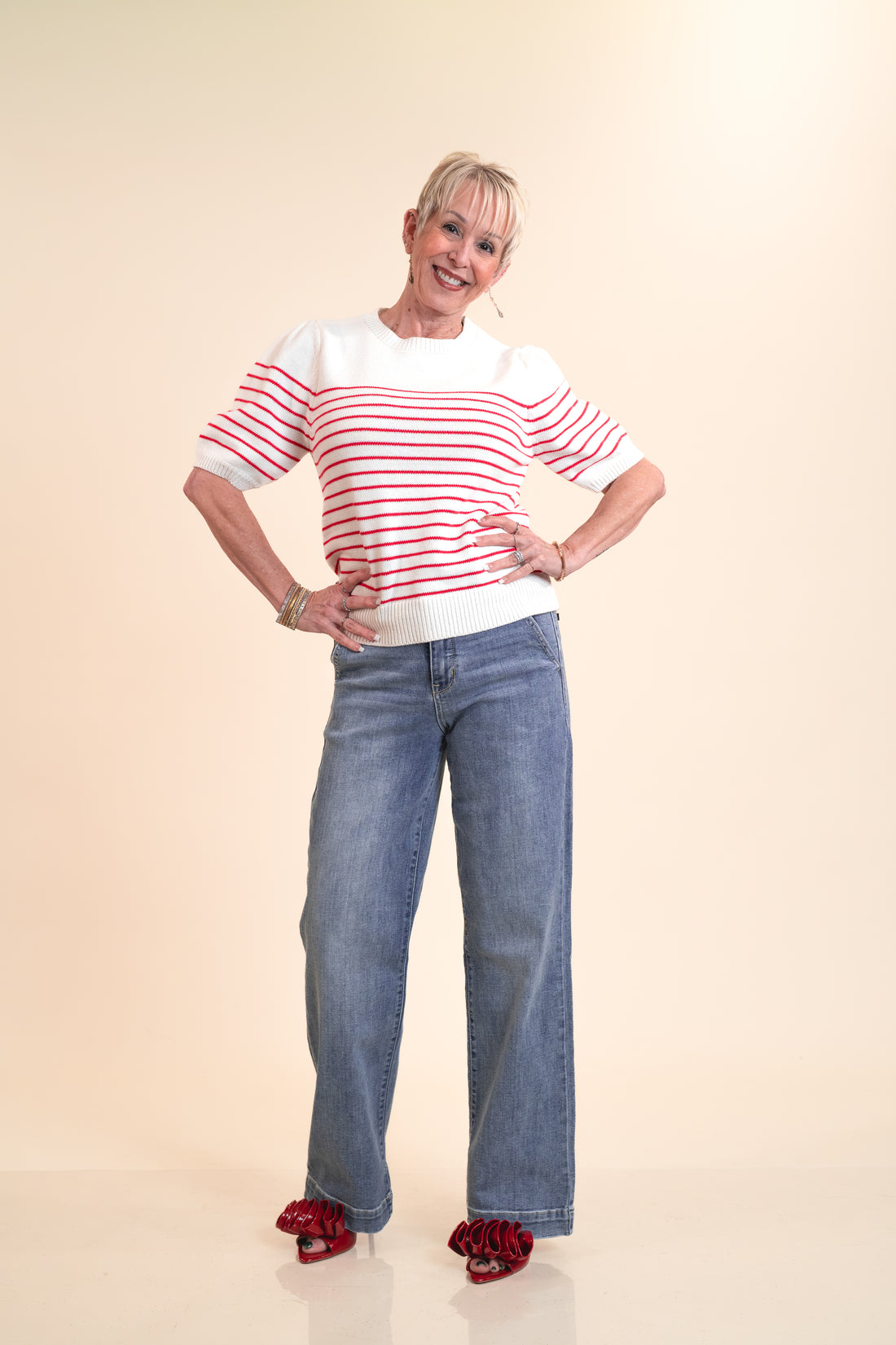 Woman wearing a red and white striped shirt and blue jeans on a beige background