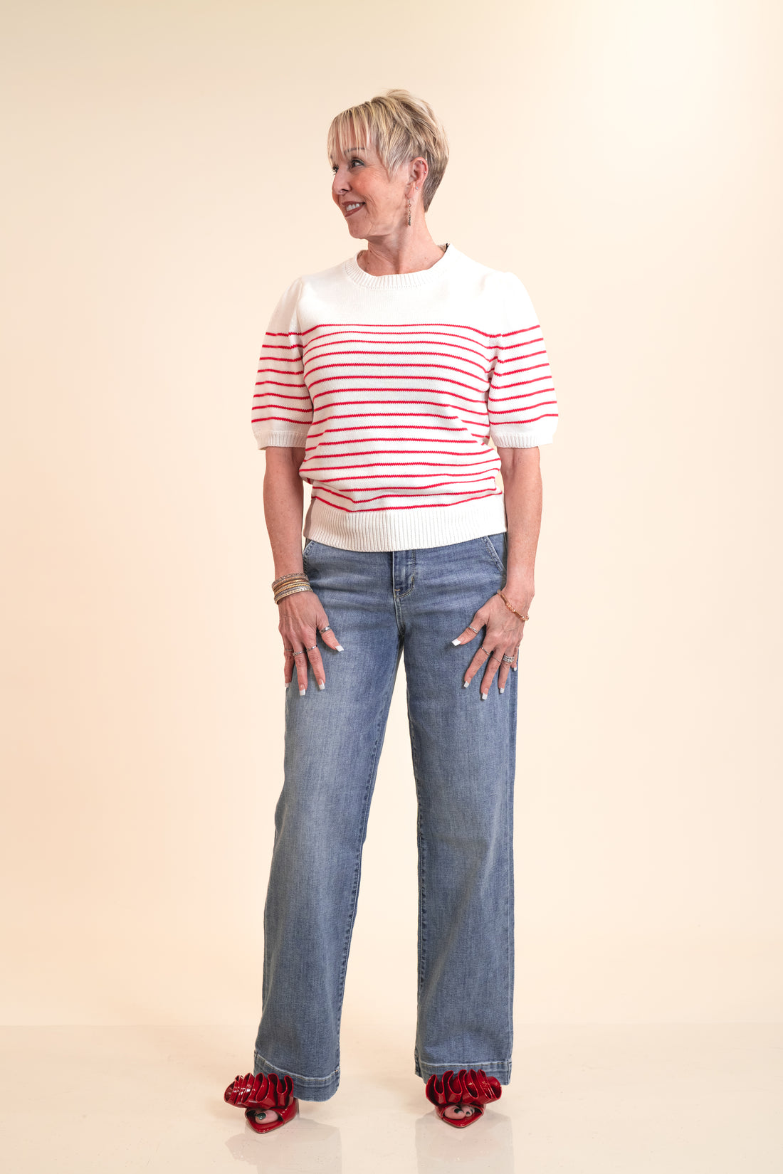 Woman wearing a red and white striped shirt and blue jeans on a beige background