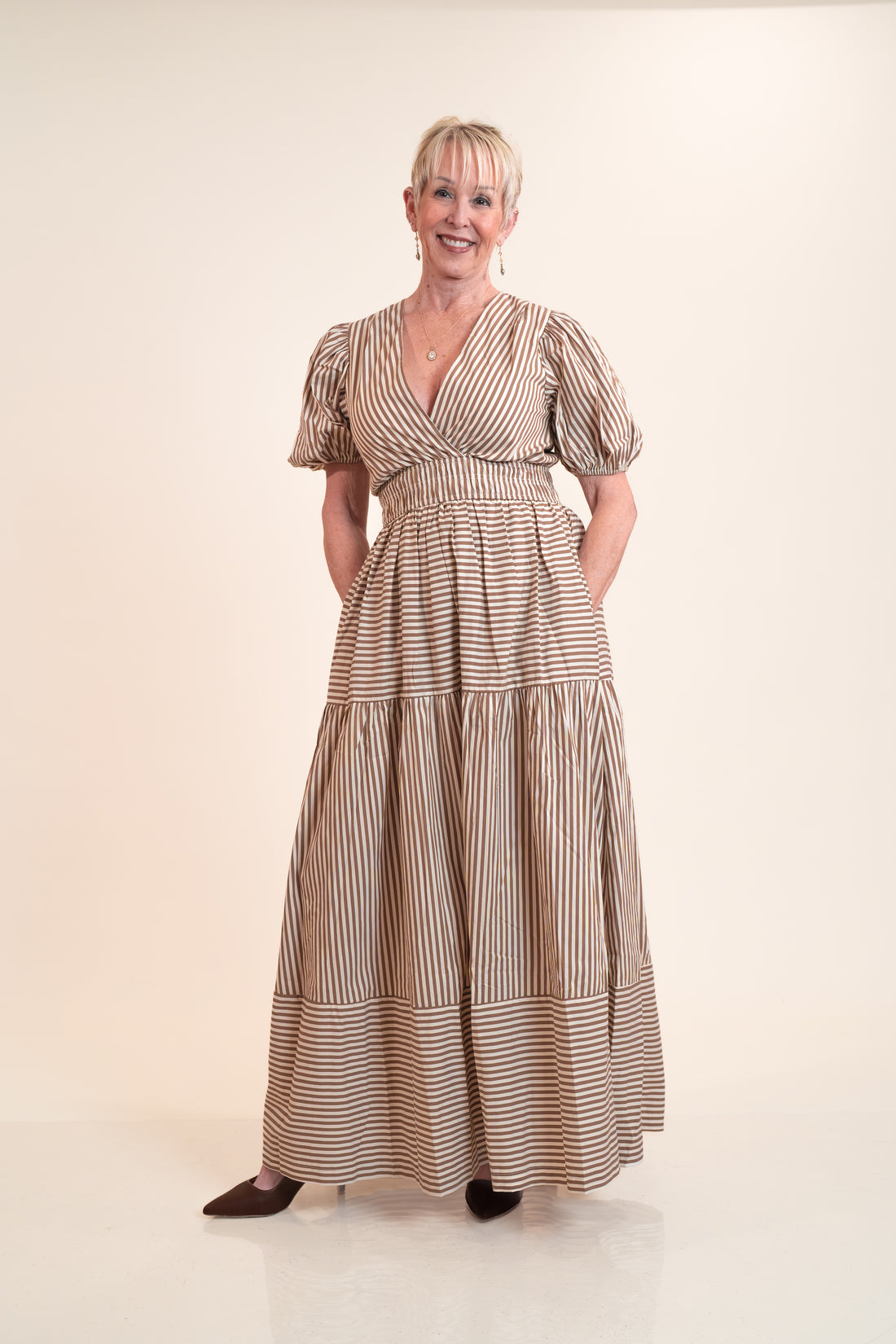 Woman wearing a long, striped dress against a plain background