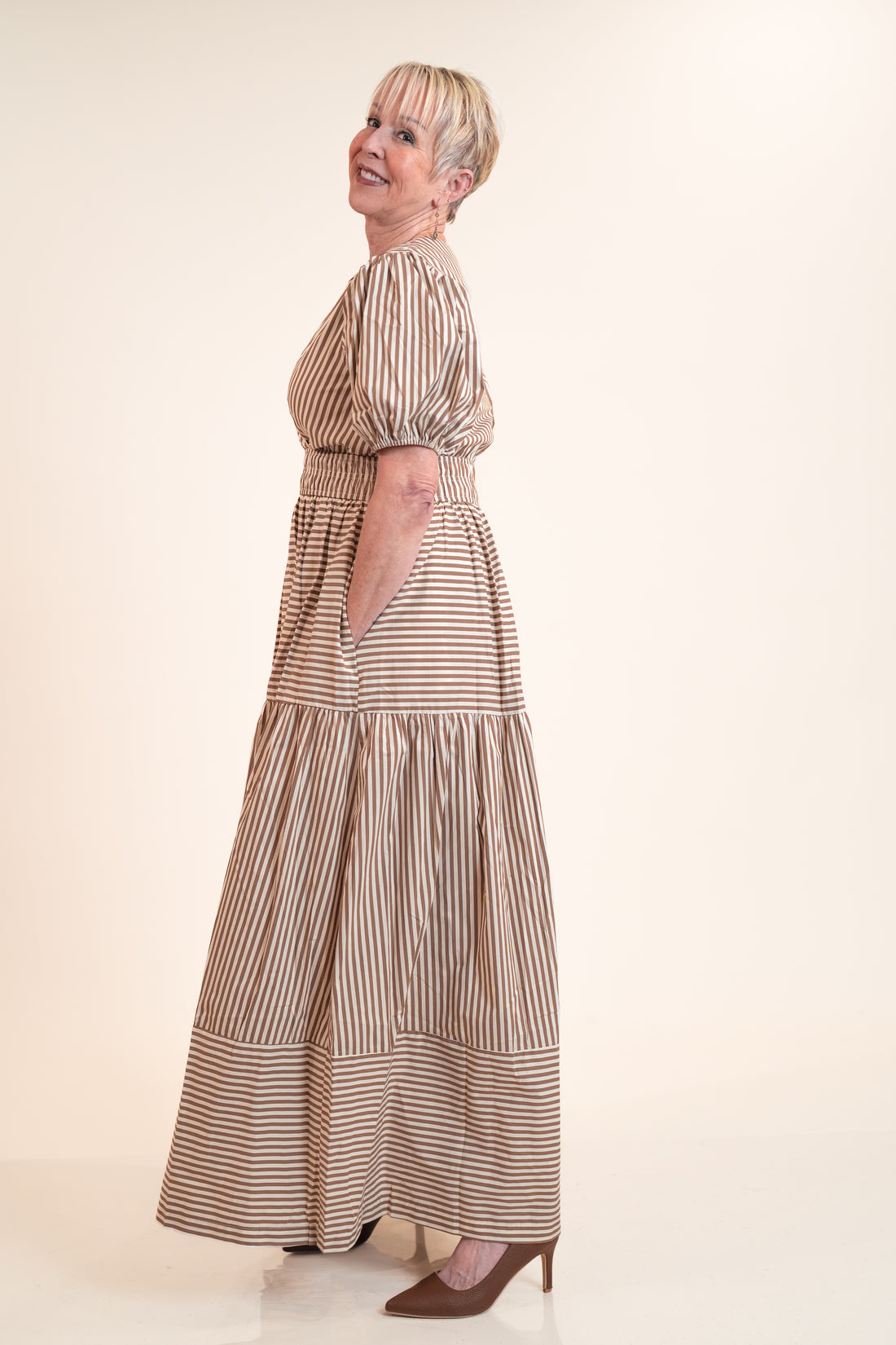 Woman wearing a long, striped dress against a plain background