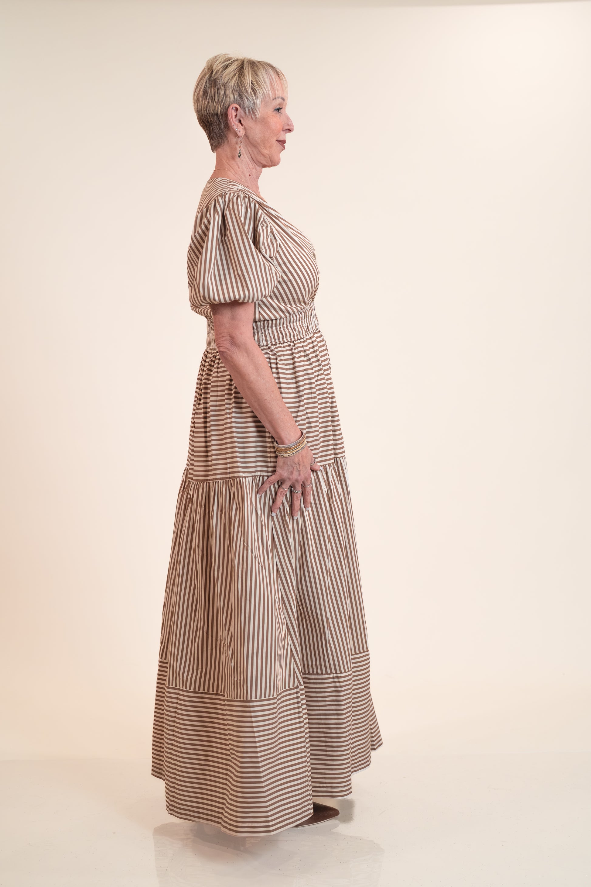 Woman wearing a long, striped dress on a plain background