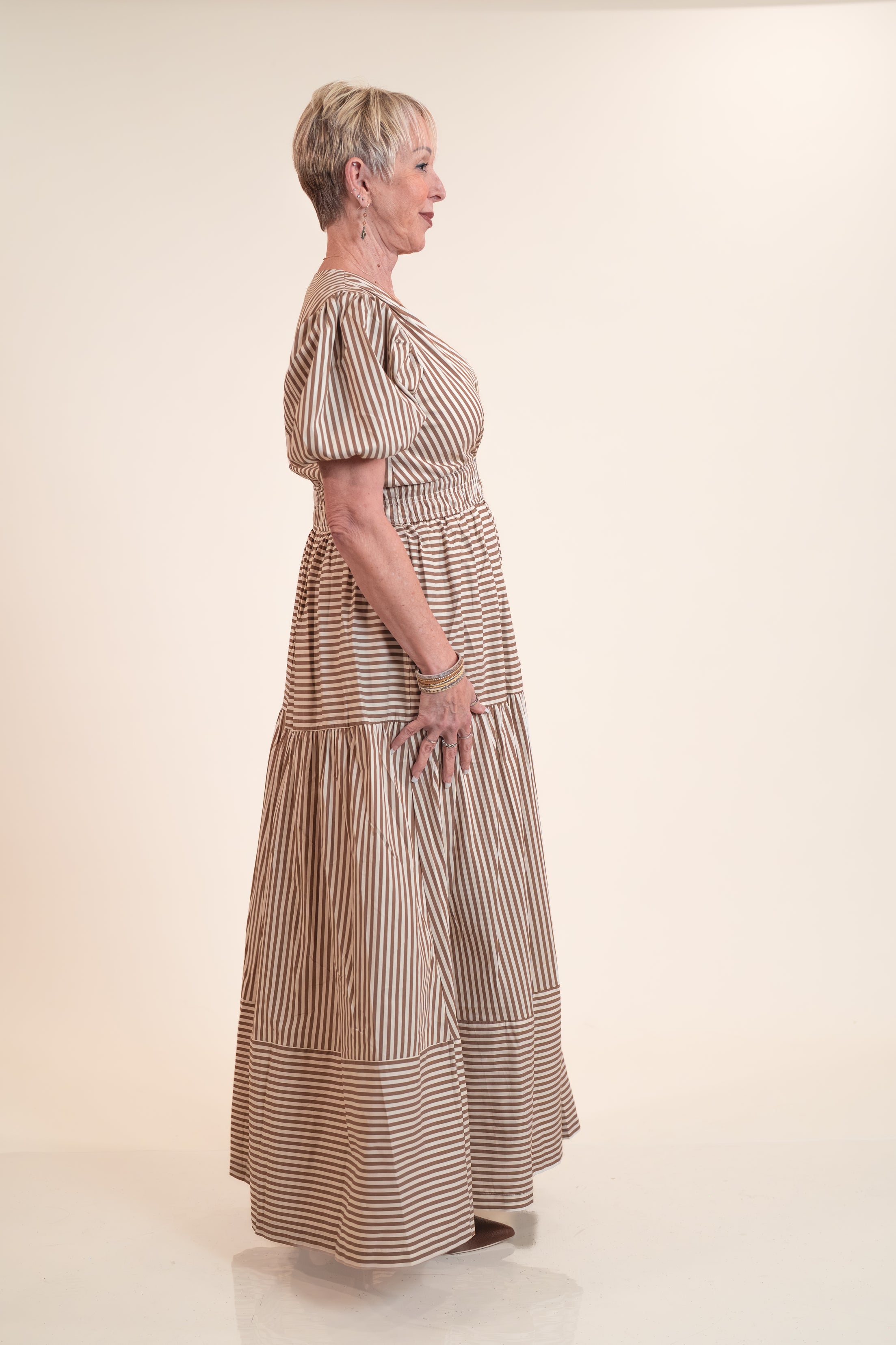 Woman wearing a long, striped dress on a plain background