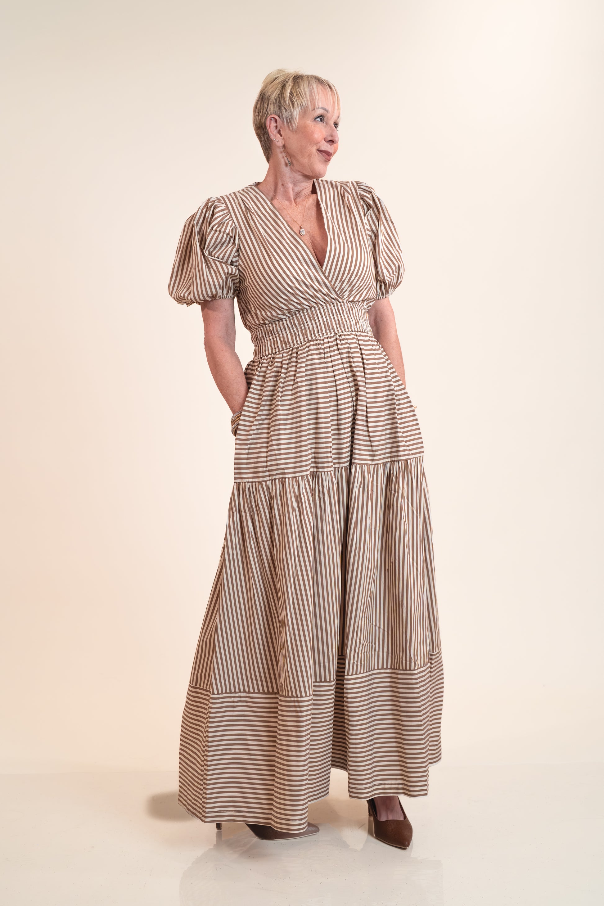 Woman wearing a long, striped dress on a plain background