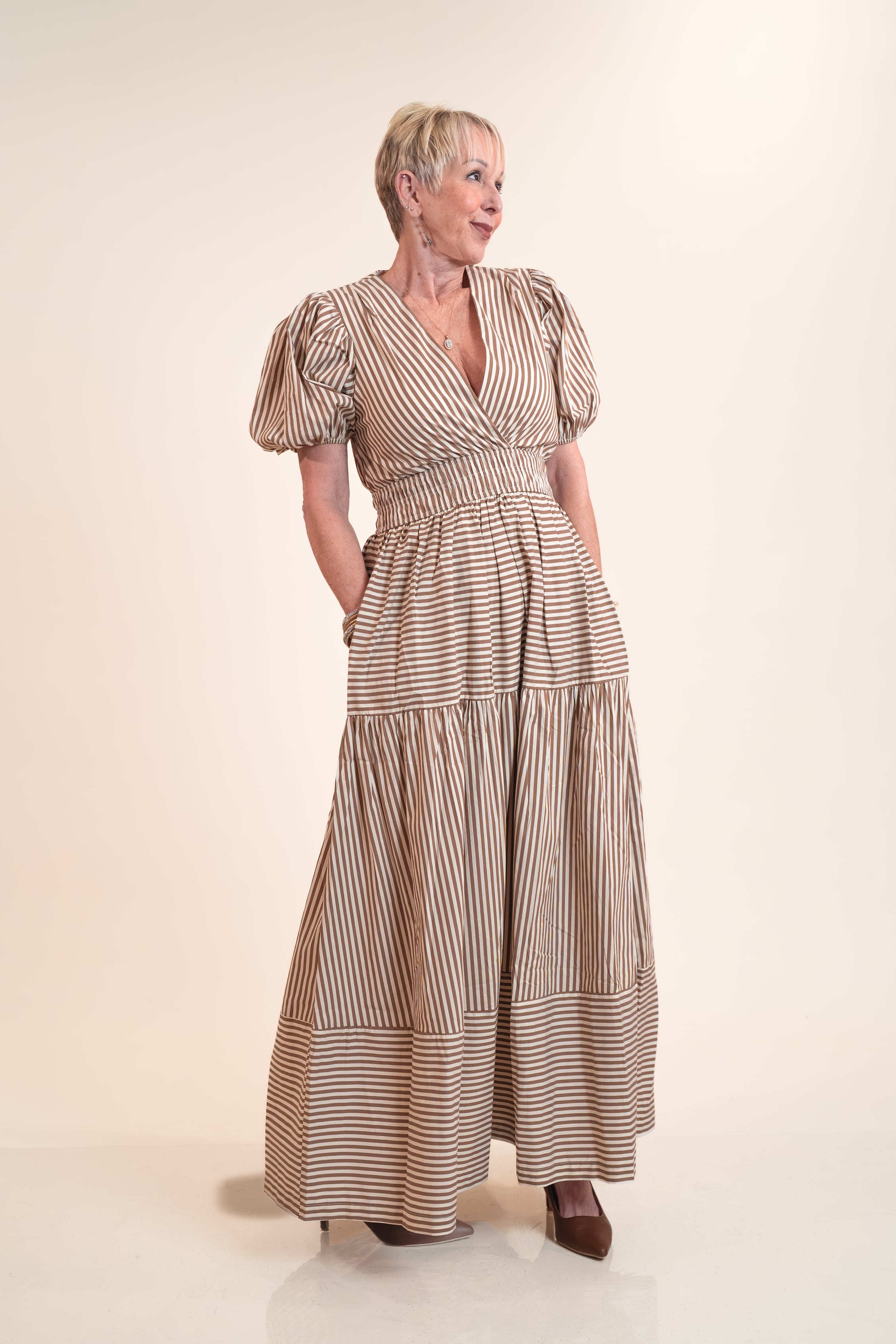 Woman wearing a long, striped dress on a plain background