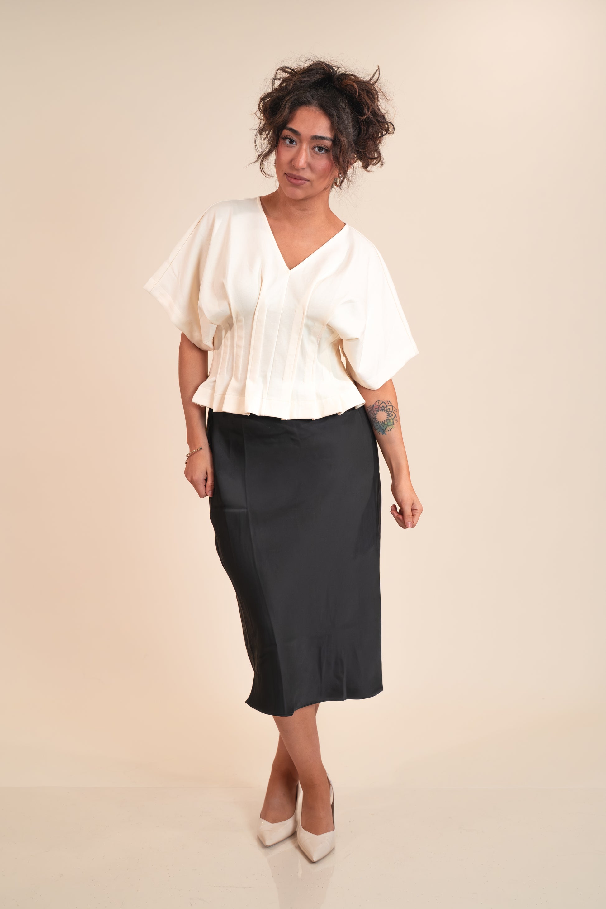 Woman wearing a white blouse and black skirt on a beige background