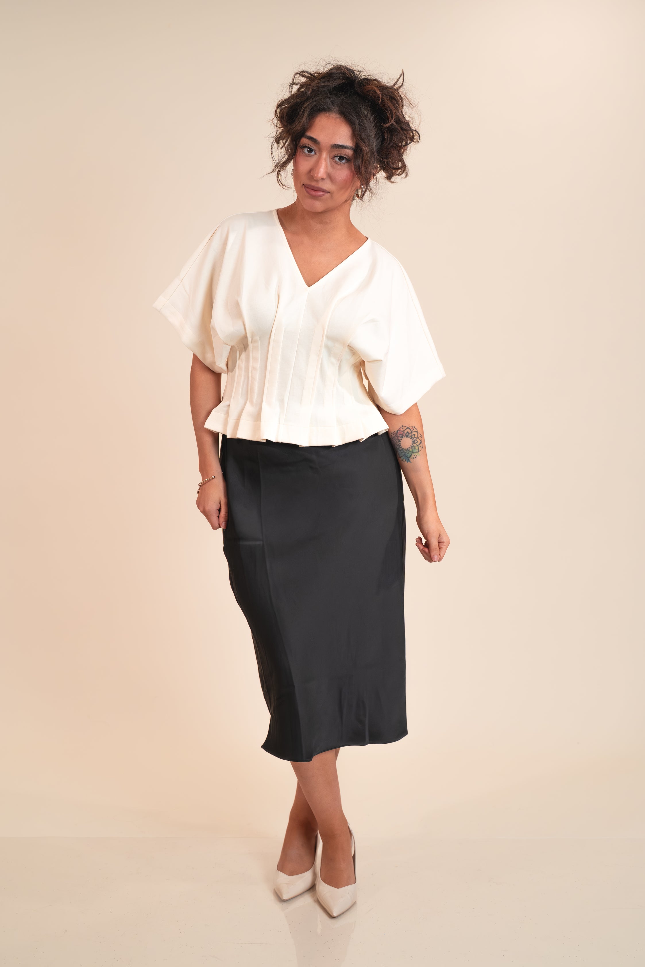 Woman wearing a white blouse and black skirt on a beige background