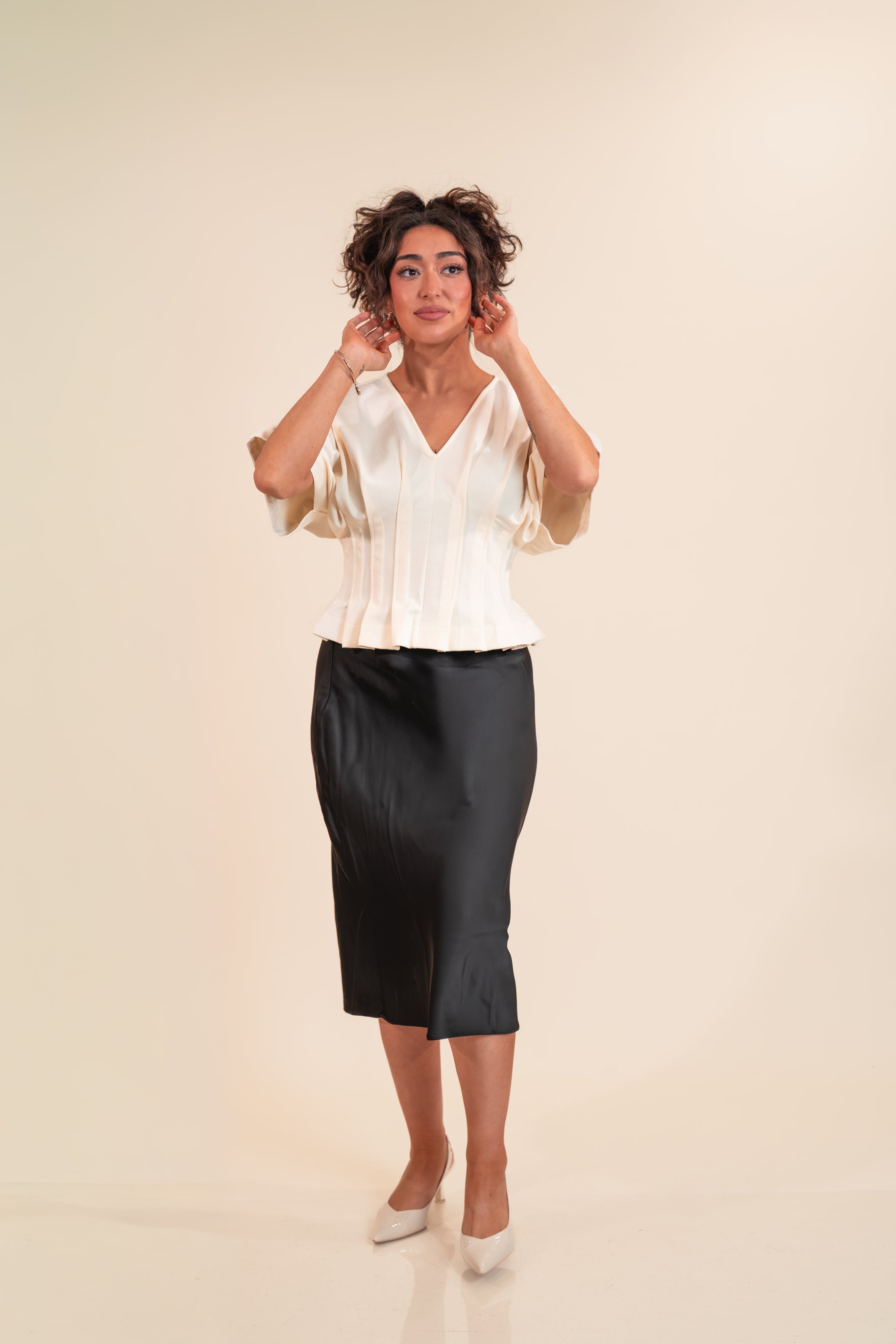 Woman wearing a white blouse and black skirt on a beige background