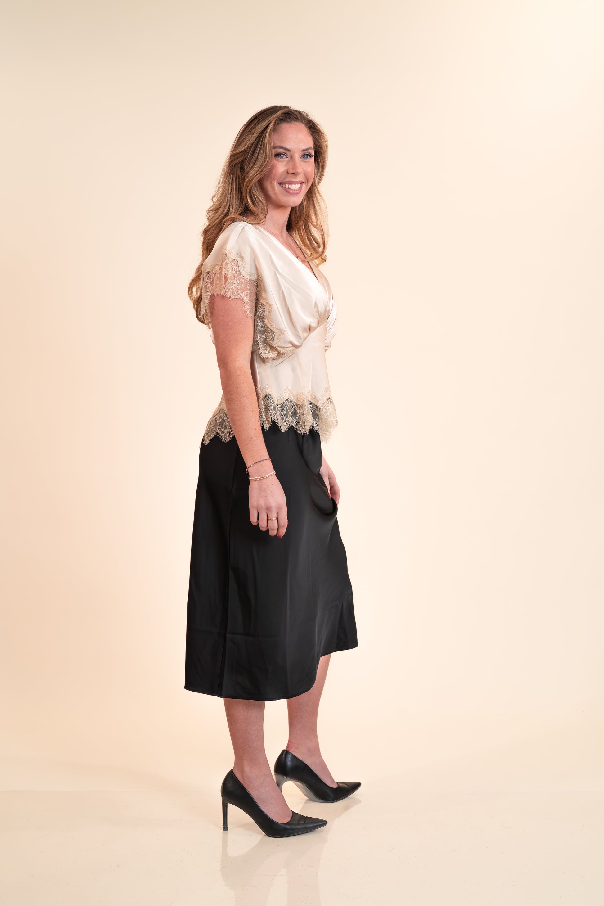Woman wearing a black skirt and white top on a beige background