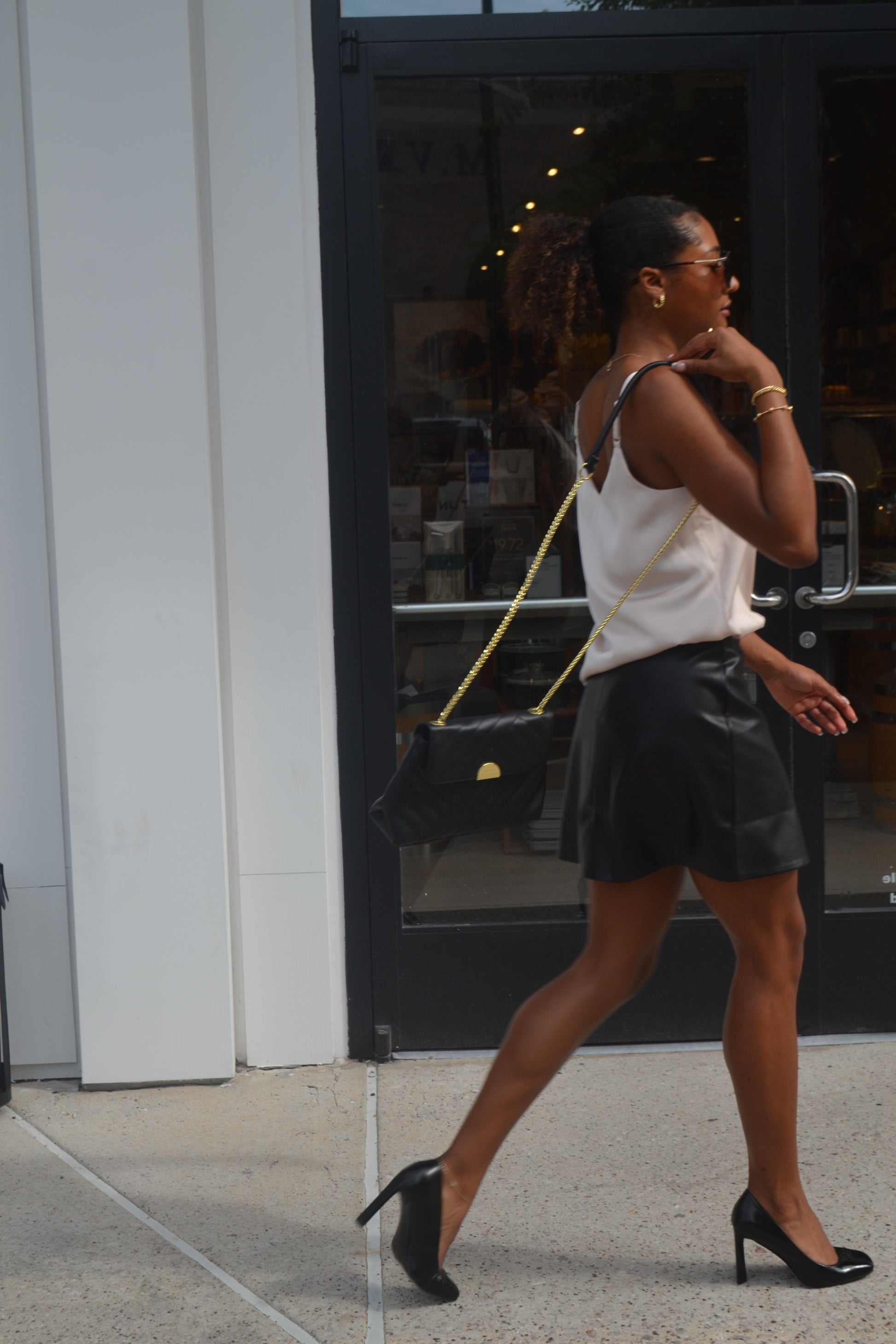 Woman posing with a handbag against a reflective surface