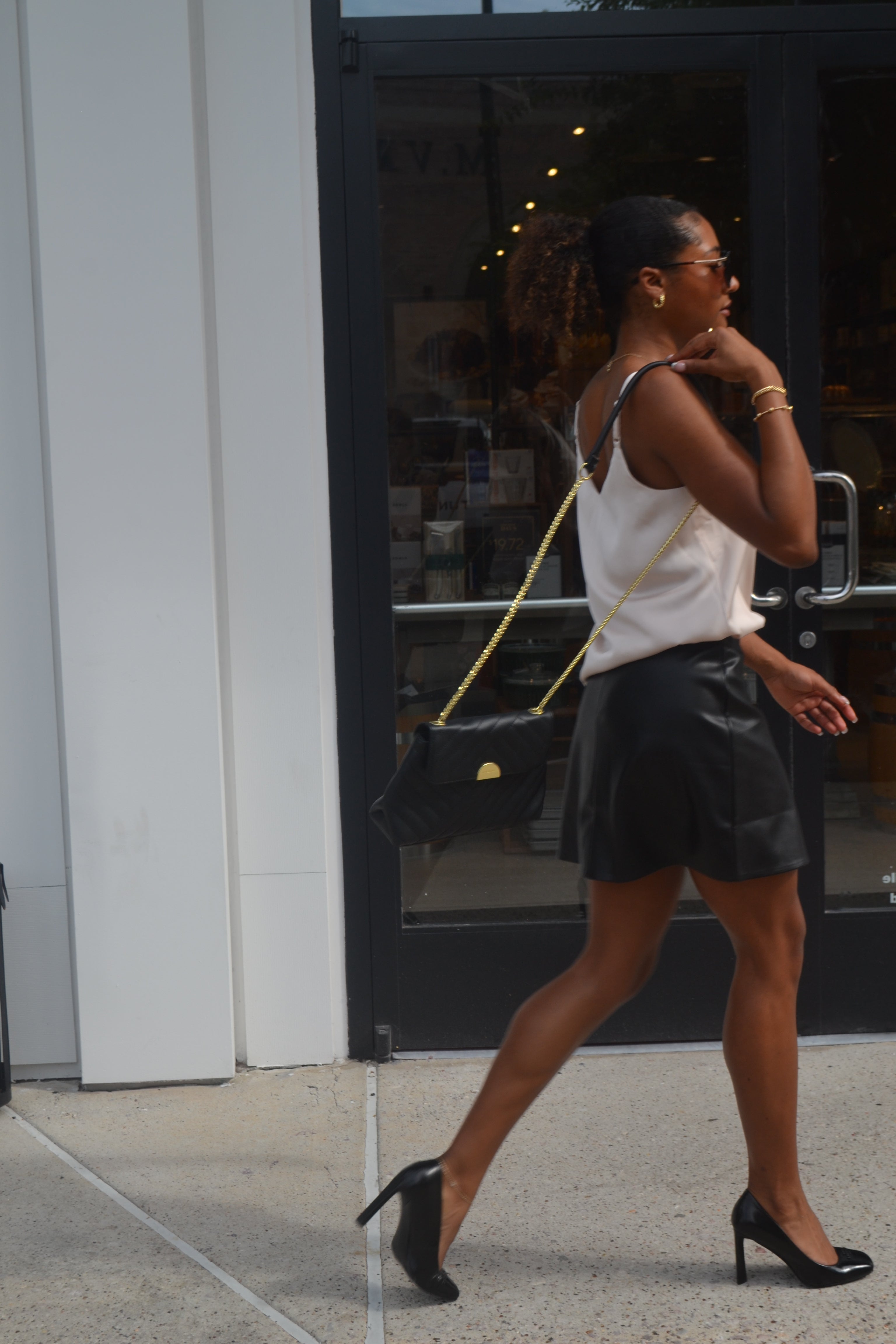 Woman posing with a handbag against a reflective surface