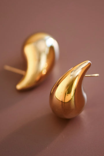 Gold earrings on a brown background
