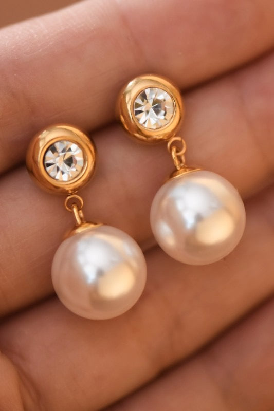 Pearl earrings with gold accents held in a hand