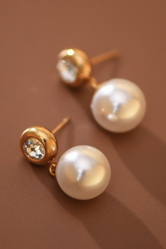 Pearl earrings with gold posts on a brown background