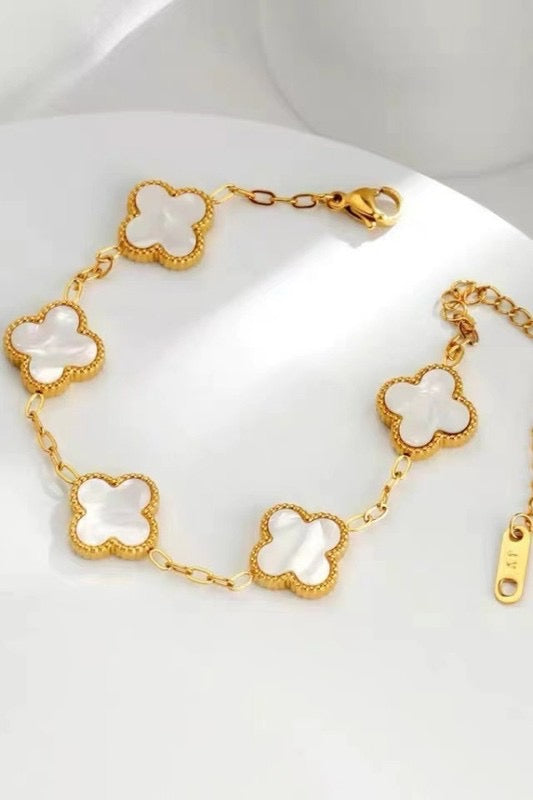 Gold bracelet with clover-shaped charms on a white background