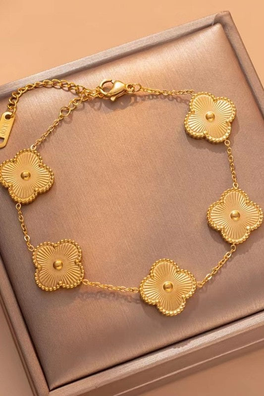 Gold bracelet with floral designs on a pink box