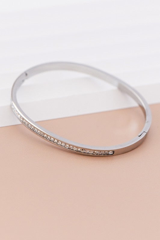 Silver bracelet with small stones on a beige surface