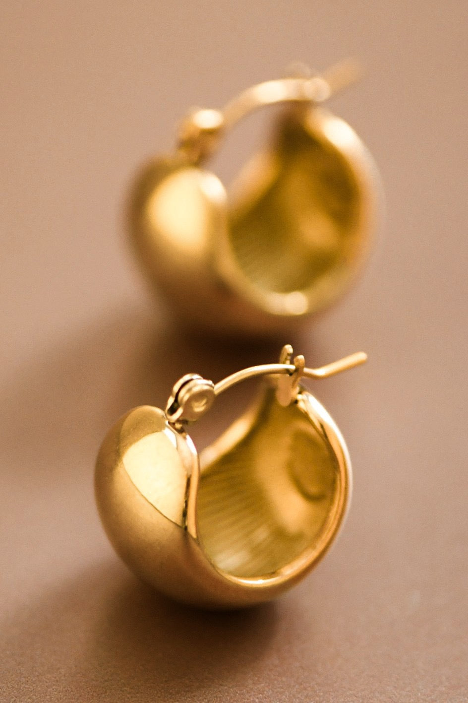 Gold hoop earrings on a brown background