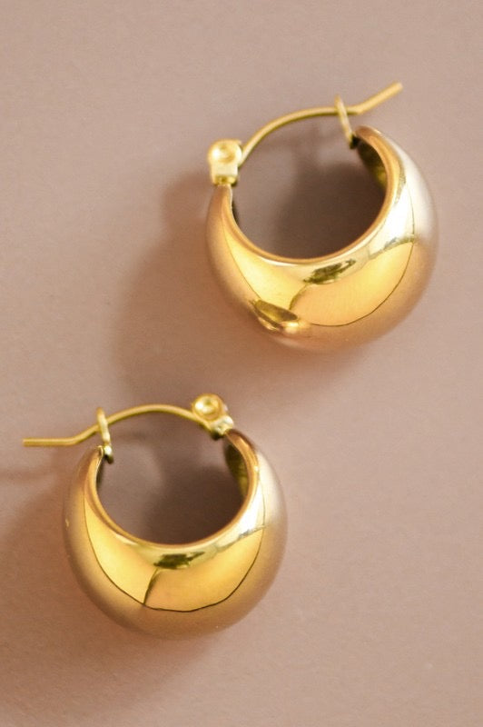 Gold hoop earrings on a beige background