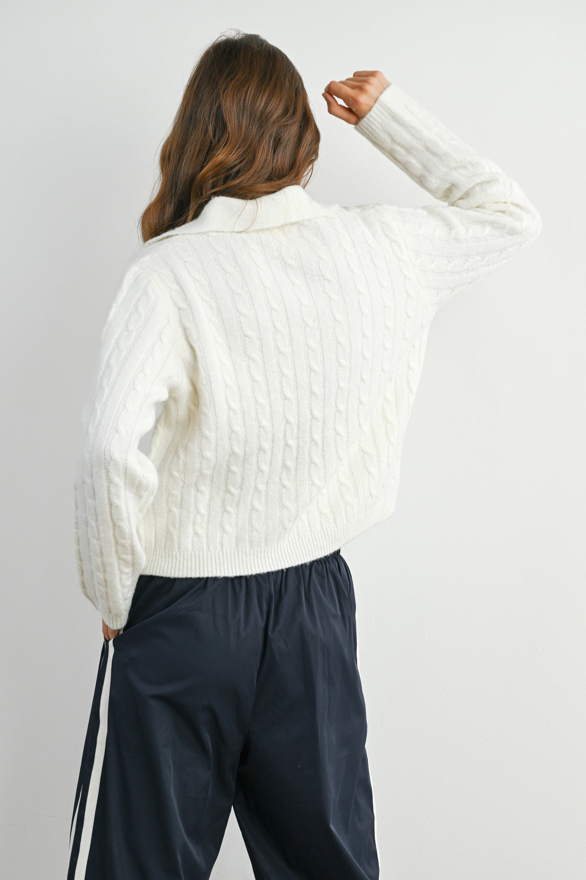 Person wearing a white textured shirt and dark pants against a plain background