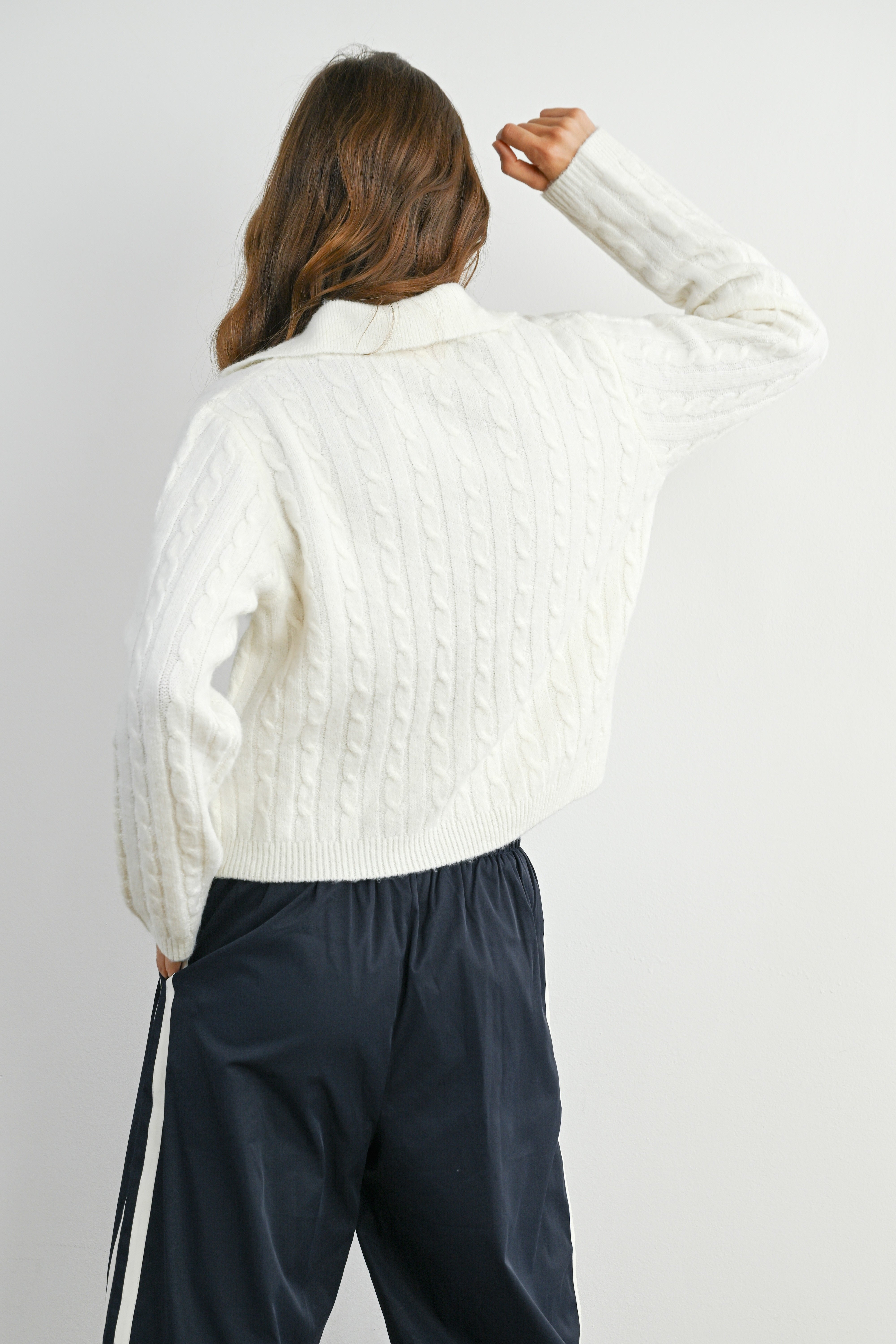 Person wearing a white textured shirt and dark pants against a plain background